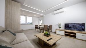 a living room with a couch and a tv and a table at Apartments Mi&Ni in Cavtat