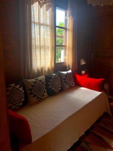 a bedroom with a bed with pillows and a window at Chalé da Conquista in Visconde De Maua