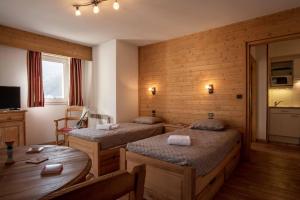 a hotel room with two beds and a table at Résidence Eureca in Brides-les-Bains