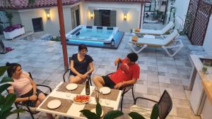 grupa ludzi siedzących przy stole na patio w obiekcie Villa Fouli w mieście Tolo