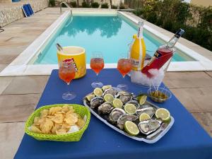 a blue table with a tray of oysters and drinks next to a pool at Cala Arenella in Sciacca