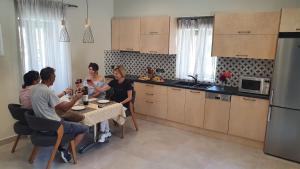 um grupo de pessoas sentadas numa mesa numa cozinha em Villa Fouli em Tolo