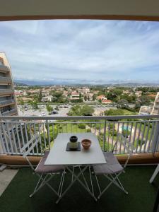 a table and chairs on a balcony with a view at Beau studio dans résidence avec piscine et vue sur la ville - 5min des plages in Mandelieu-La Napoule