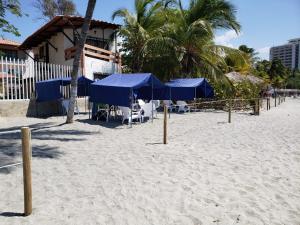a beach with blue umbrellas and chairs on the sand at Hospedaje Villa Naloy in Santa Marta