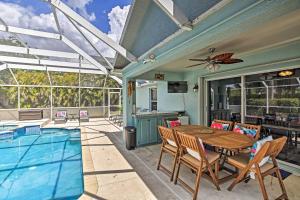 a patio with a table and a swimming pool at Modern Beach Retreat with Pool, Hot Tub, and Patio! in Fort Myers