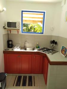 a kitchen with red cabinets and a sink and a window at Appartement cosy Le Marin 60 m² + jardin in Le Marin +8 photos
