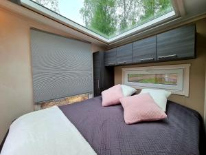 um quarto com uma cama grande com almofadas cor-de-rosa e brancas em Mansikkaharju Holiday Camp em Leppävirta