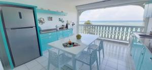 una cucina con tavolo e un balcone con vista sull'oceano di Le Vanille a Saint-François