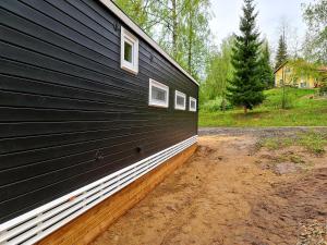 ein schwarzes Gebäude mit Seitenfenstern in der Unterkunft Mansikkaharju Holiday Camp in Leppävirta