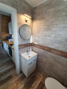 La salle de bains est pourvue d'un lavabo et d'un miroir. dans l'établissement Willa Zacisze apartament 12, à Kąty Rybackie