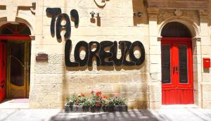 a building with a sign on the side of it with flowers at Ta’ Lorenzo in San Lawrenz