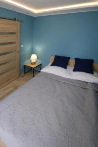 a bedroom with a large bed with a blue wall at Apartament Navigare in Kołobrzeg