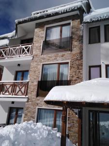 Zlatna Kruna - Lux Apartments Kopaonik في كوباونيك: مبنى فيه ثلج على الارض امامه