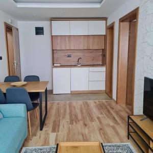 Zlatna Kruna - Lux Apartments Kopaonik في كوباونيك: غرفة معيشة بها طاولة ومطبخ