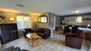 a living room with chairs and a table and a kitchen at Het Roodborstje in Otterlo