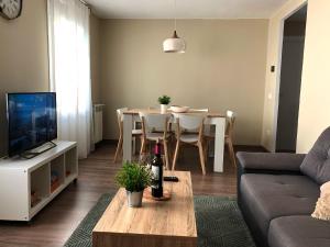 een woonkamer met een bank en een tafel met een fles wijn bij Apartamento acogedor y familiar - WiFi+Chromecast in Puigcerdà