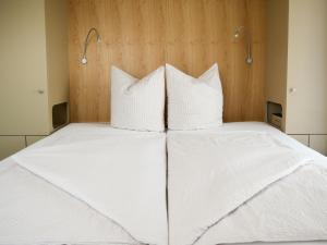 Una cama con sábanas blancas y almohadas. en 5Rooms Frühstückspension en Sankt Stefan im Rosental