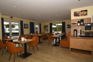 un restaurant avec des tables en bois et des chaises orange dans l'établissement Ellen Hotel, à Flensbourg
