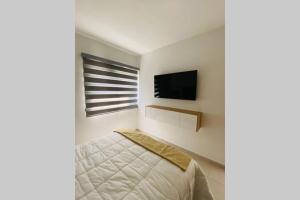 um quarto com uma cama e uma televisão na parede em Modern Decor Apartment near ocean em Mazatlán