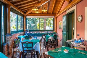 una sala da pranzo con tavoli e sedie verdi e finestre di ALHAMBRA - B&B - Guest House di Charme a Giarre