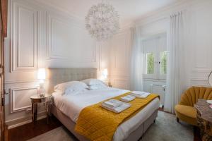 a white bedroom with a bed and a chandelier at Casa da Fonte - Holiday Apartments in Cascais