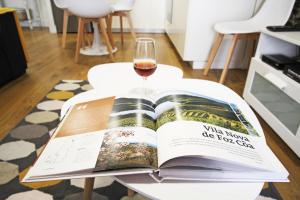 an open book on a table with a glass of wine at Casa do Tablado - Foz Côa in Vila Nova de Foz Coa