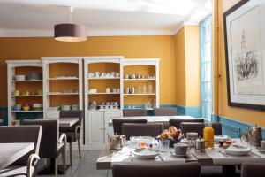 a dining room with tables and chairs and yellow walls at Hôtel l'Amphithéâtre in Nîmes