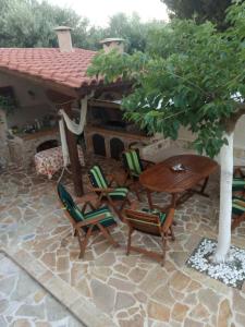 patio ze stołem i krzesłami na kamiennej podłodze w obiekcie Villa Tsios w mieście Artemida