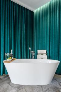 uma banheira na casa de banho com cortinas verdes em Pokoje, Noclegi, Apartamenty Dune Resort Łeba em Łeba