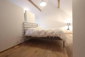 Łóżko w białym pokoju z drewnianą podłogą w obiekcie Loft à la campagne/ 1ère occupation w mieście Visé