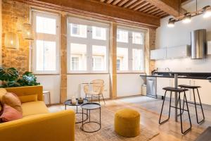 a living room with a couch and chairs and a kitchen at Honorê, Suite Saint Georges in Lyon