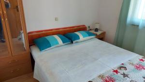 a bedroom with a bed with blue and white pillows at Apartment Krizanovic in Malinska
