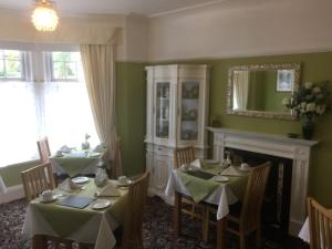 een eetkamer met 2 tafels en een open haard bij The Hilary Guesthouse in Llandudno