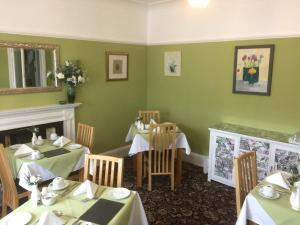 a dining room with two tables and a fireplace at The Hilary Guesthouse in Llandudno