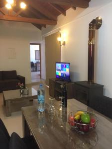 a living room with a table with a bowl of fruit and a television at Love Holiday Suite 2 in Tris Elies
