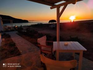a wooden table and chairs with the sunset in the background at Sunset Studios & Rooms in Antiparos
