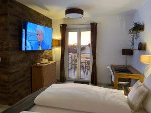 1 dormitorio con 1 cama y TV en la pared en Haus Langweid - Moderne Ferienwohnungen mit Luxus im Inntal, en Neubeuern