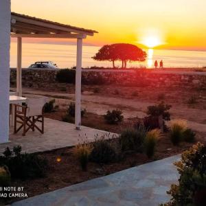 a table and a chair under a pavilion with the sunset at Sunset Studios & Rooms in Antiparos