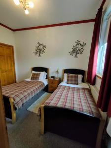 two beds in a room with red curtains at The Old Smiddy Cottage and Apartment in Balloch