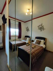 a hotel room with two beds and a mirror at The Old Smiddy Cottage and Apartment in Balloch
