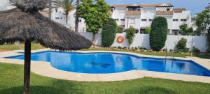ein Pool mit einem Strohschirm und einem Gebäude in der Unterkunft Serenity Luxury , Puerto Banús Marbella in Marbella