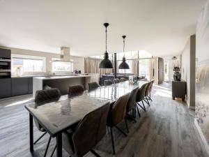 comedor y cocina con mesa larga y sillas en Maison Jolie en Sint Annaland