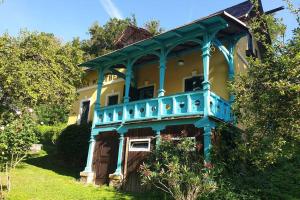 a blue and yellow house with a blue balcony at Alte Villa 400m2 Seegrund nur für euch - old villa with 400m2 beach just for you in Maria Wörth