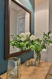 lustro siedzące na drewnianym stole z kwiatami w obiekcie Irida Apartments w mieście Leptokaria