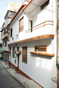 un edificio blanco con ventanas de madera en una calle en Casa Saga - All Suites, en Río de Janeiro