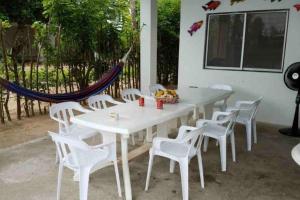 une table et des chaises blanches ainsi qu'un hamac dans l'établissement PLAYA BLANCA SANANTERO CORDOBA las palmeras D’JC, à San Antero