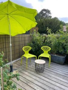 dos sillas amarillas y una sombrilla en una cubierta en Et c'est une autre histoire studio, en Léon
