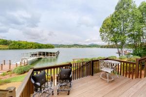 a deck with chairs and a table and a boat on the water at Lake Chatuge Retreat in Hiawassee