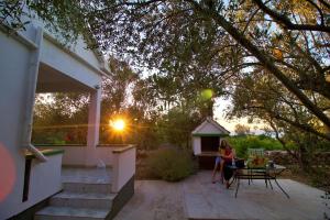 a woman sitting at a table on the patio of a house at Holiday house Silvana in Ždrelac