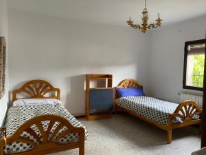 1 dormitorio con 2 camas y lámpara de araña en Casa Pueblo, en Navas de Estena